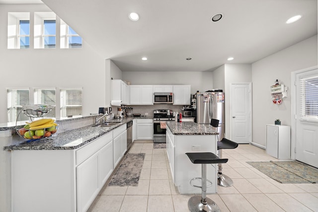 kitchen featuring sink, stainless steel appliances, a healthy amount of sunlight, and dark stone counters