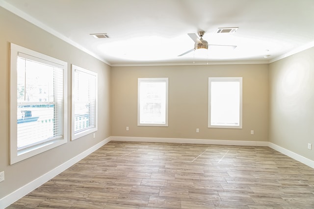 unfurnished room featuring a wealth of natural light, crown molding, and light wood-type flooring