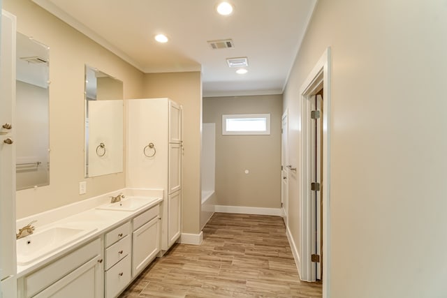 bathroom featuring a bath, crown molding, hardwood / wood-style flooring, and vanity