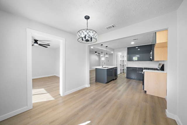 kitchen with a kitchen island with sink, hardwood / wood-style flooring, sink, decorative light fixtures, and a textured ceiling