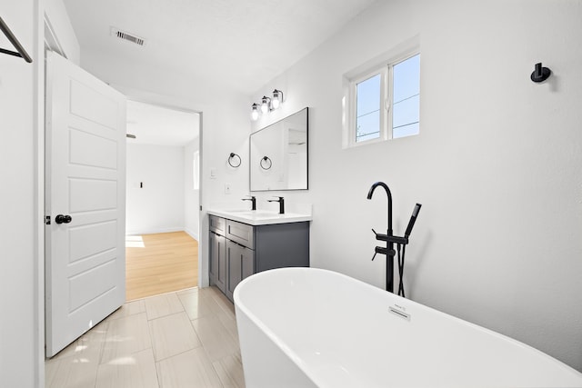 bathroom featuring vanity, a tub to relax in, and tile patterned flooring