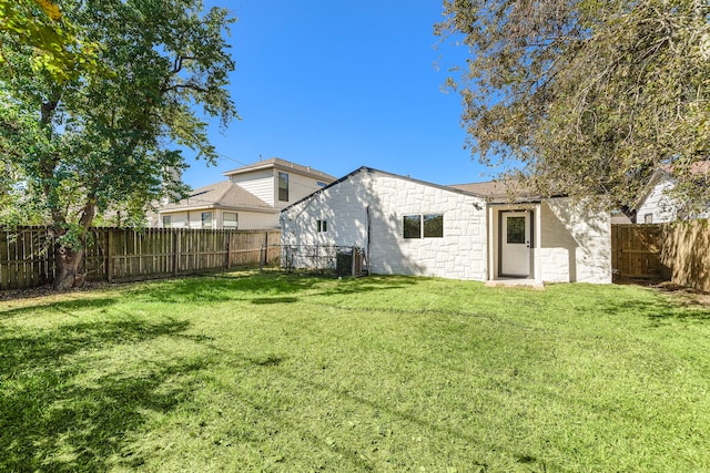 rear view of house featuring a lawn and central AC unit