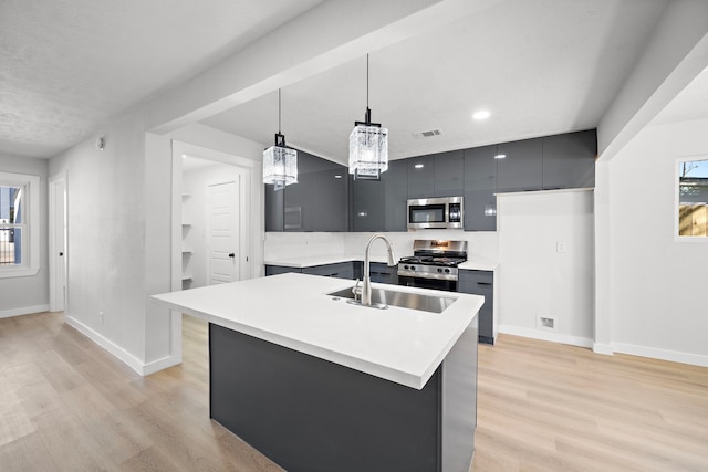 kitchen featuring appliances with stainless steel finishes, decorative light fixtures, sink, and light wood-type flooring