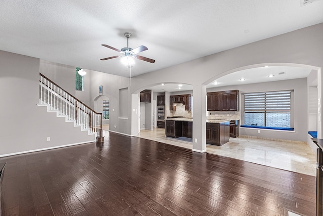 unfurnished living room featuring ceiling fan, light hardwood / wood-style flooring, and a textured ceiling