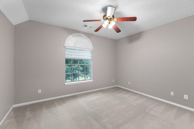 carpeted empty room with ceiling fan, lofted ceiling, and a textured ceiling