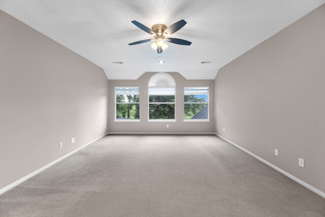 carpeted spare room featuring ceiling fan, a textured ceiling, and vaulted ceiling