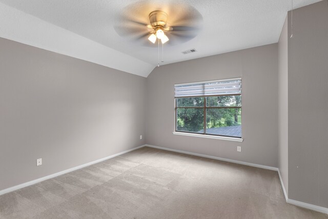 unfurnished room featuring a textured ceiling, ceiling fan, light colored carpet, and lofted ceiling