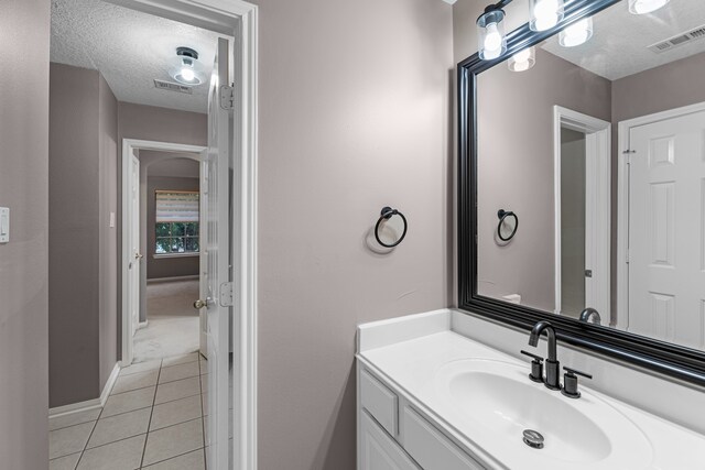 bathroom with tile patterned flooring, a textured ceiling, and vanity