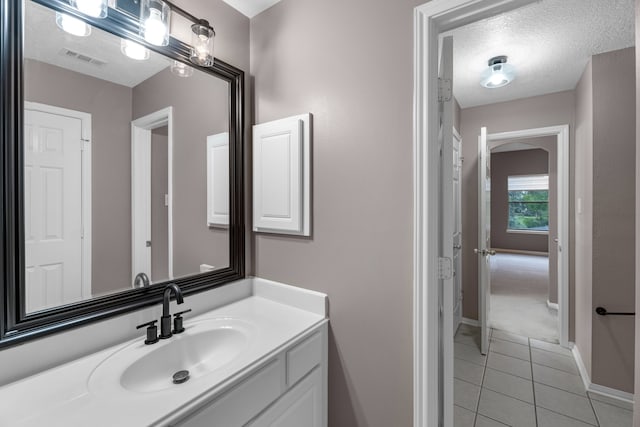 bathroom with tile patterned flooring, vanity, and a textured ceiling