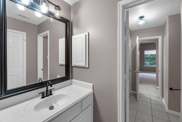 bathroom with tile patterned flooring, vanity, and a textured ceiling