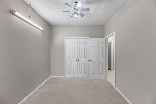 unfurnished bedroom with ceiling fan, light colored carpet, a textured ceiling, and a closet