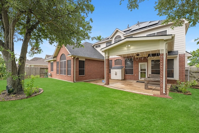 rear view of house with a lawn, a patio, and solar panels