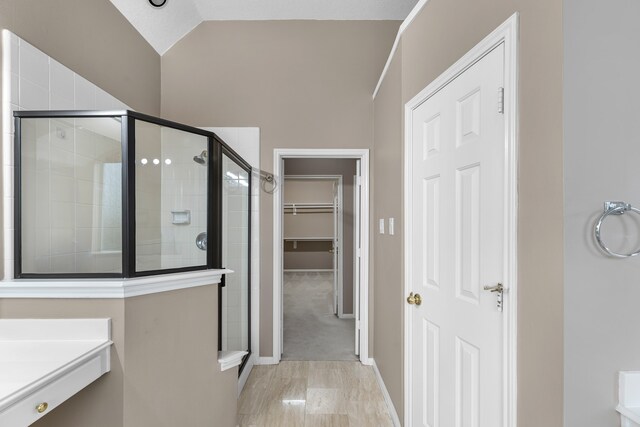 bathroom featuring vaulted ceiling and a shower with shower door