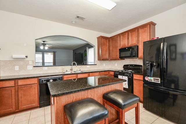 kitchen featuring black appliances, sink, a kitchen bar, a kitchen island, and light tile patterned floors