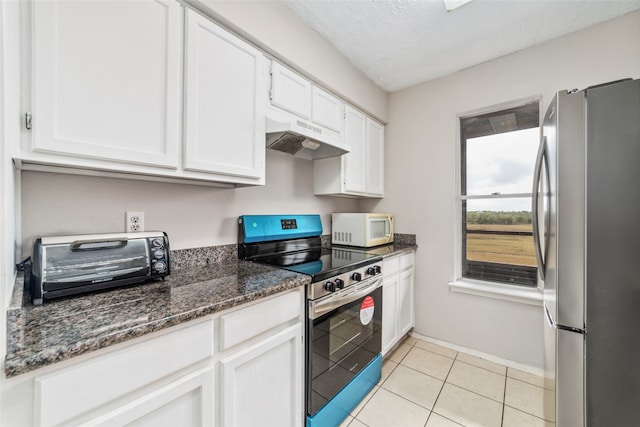 kitchen with white cabinets, appliances with stainless steel finishes, a textured ceiling, dark stone counters, and light tile patterned flooring