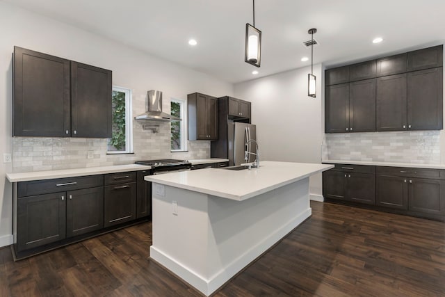 kitchen with wall chimney exhaust hood, dark brown cabinets, hanging light fixtures, and dark hardwood / wood-style floors