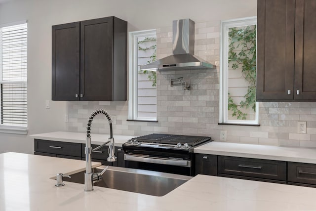 kitchen with wall chimney exhaust hood, a healthy amount of sunlight, and backsplash