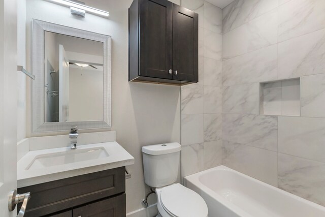 full bathroom with vanity, tiled shower / bath combo, and toilet