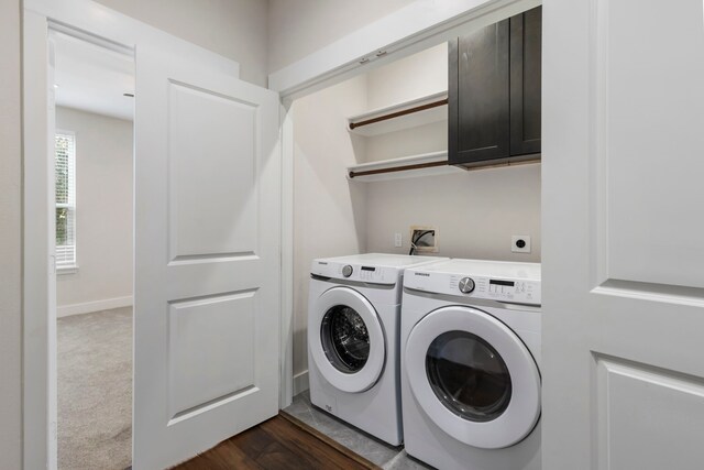 laundry area with dark hardwood / wood-style flooring, washer and clothes dryer, and cabinets