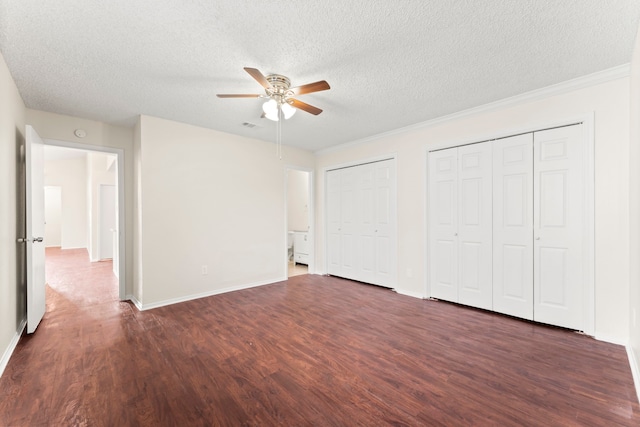 unfurnished bedroom featuring dark hardwood / wood-style floors, multiple closets, a textured ceiling, and ceiling fan