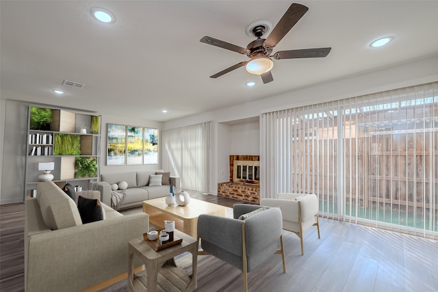 living room with ceiling fan, wood-type flooring, and a fireplace