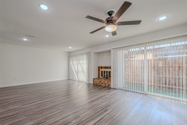 unfurnished living room with hardwood / wood-style floors, a healthy amount of sunlight, a fireplace, and ceiling fan