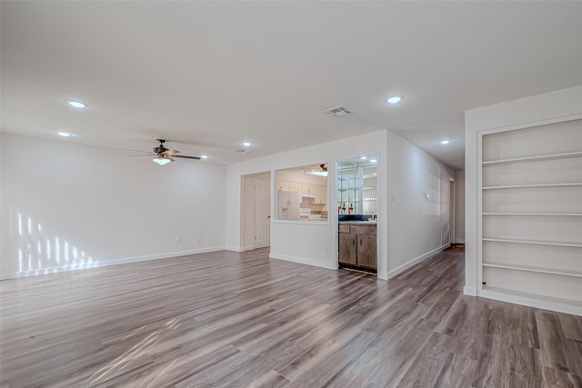 unfurnished living room featuring light hardwood / wood-style flooring, built in features, and ceiling fan