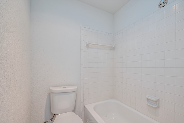 bathroom with toilet and tiled shower / bath