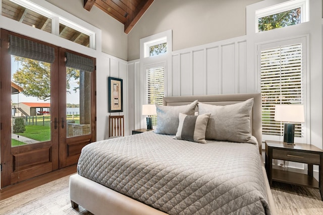 bedroom featuring access to exterior, high vaulted ceiling, light hardwood / wood-style flooring, wooden ceiling, and beam ceiling