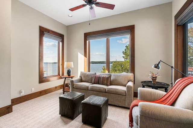 living room featuring a water view, light colored carpet, and ceiling fan