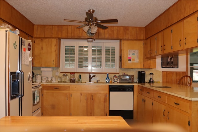 kitchen with a textured ceiling, wooden walls, sink, and white appliances