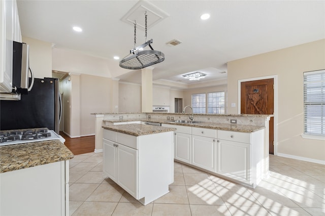 kitchen with kitchen peninsula, white cabinets, a center island, and sink