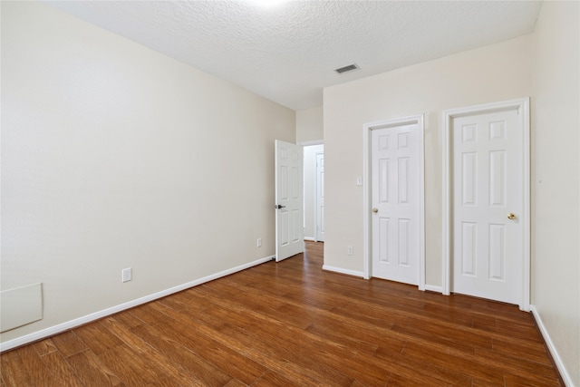 unfurnished bedroom featuring a textured ceiling and dark hardwood / wood-style flooring