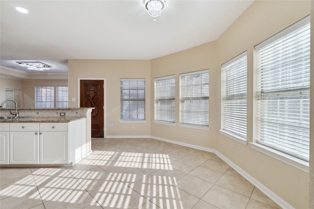 kitchen featuring sink, white cabinets, light stone counters, and light tile patterned floors