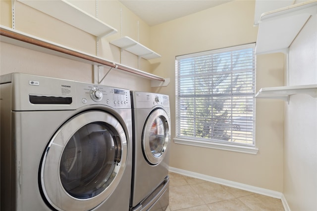 clothes washing area featuring a wealth of natural light, washer and clothes dryer, and light tile patterned floors