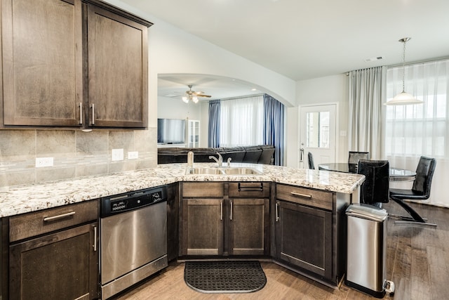 kitchen with kitchen peninsula, dark brown cabinets, sink, stainless steel dishwasher, and light hardwood / wood-style floors