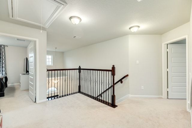 hall with a textured ceiling and light colored carpet