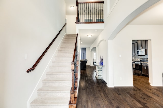 stairs featuring hardwood / wood-style flooring and a high ceiling