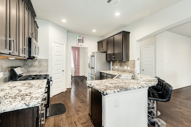 kitchen with tasteful backsplash, appliances with stainless steel finishes, sink, dark hardwood / wood-style flooring, and light stone counters