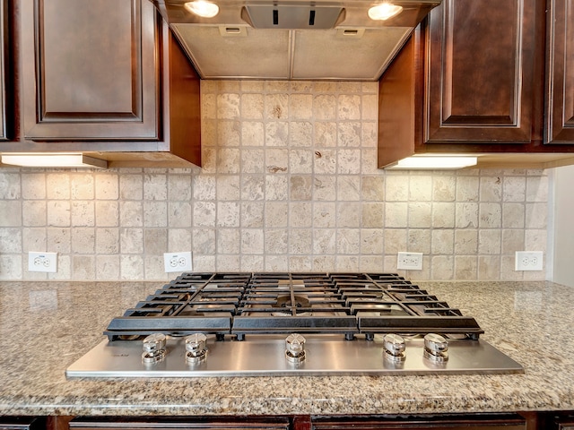 kitchen with decorative backsplash, stainless steel gas stovetop, and light stone countertops