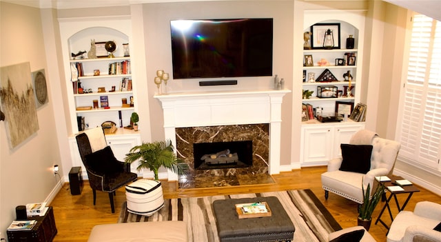 living room with light hardwood / wood-style floors, a premium fireplace, and built in shelves