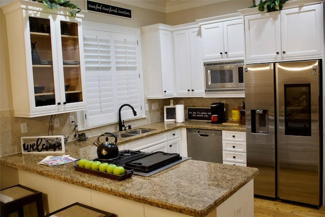 kitchen featuring light stone countertops, sink, kitchen peninsula, white cabinetry, and stainless steel appliances