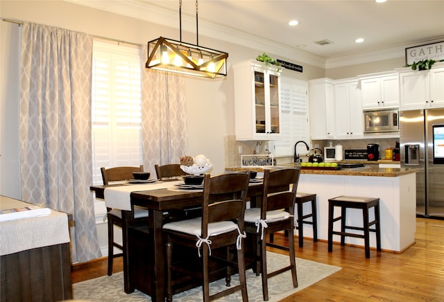 dining room featuring ornamental molding and light wood-type flooring