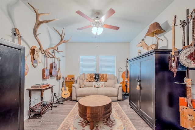 living area with ceiling fan and light hardwood / wood-style flooring