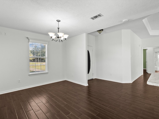 unfurnished room with a notable chandelier, a textured ceiling, and dark hardwood / wood-style flooring