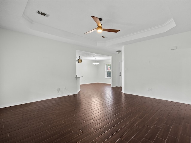 empty room featuring a raised ceiling, dark hardwood / wood-style flooring, and ceiling fan with notable chandelier