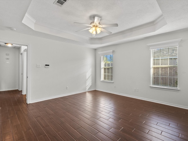 unfurnished room with ceiling fan, a healthy amount of sunlight, a tray ceiling, and dark hardwood / wood-style floors