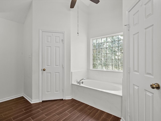 bathroom with lofted ceiling, hardwood / wood-style flooring, a washtub, and ceiling fan