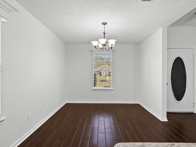 unfurnished dining area featuring a textured ceiling, washer / clothes dryer, dark hardwood / wood-style flooring, and an inviting chandelier