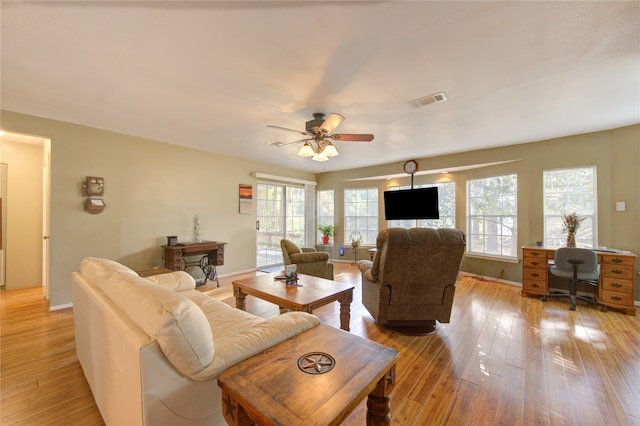 living room with a wealth of natural light, light hardwood / wood-style flooring, and ceiling fan